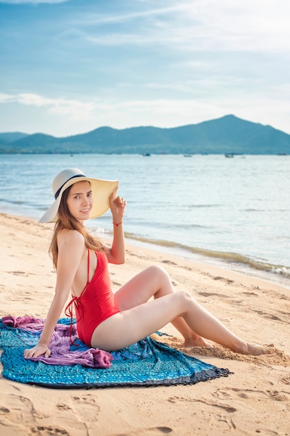 Beautiful woman in red swimsuit  is sitting on the beach 