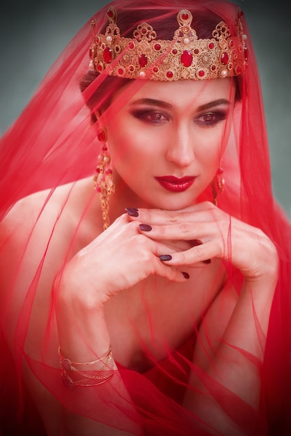 Beautiful woman in red veil in long red dress and in royal crown