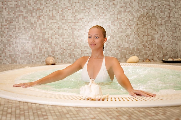 Beautiful woman relaxing in Jacuzzi at the spa center.