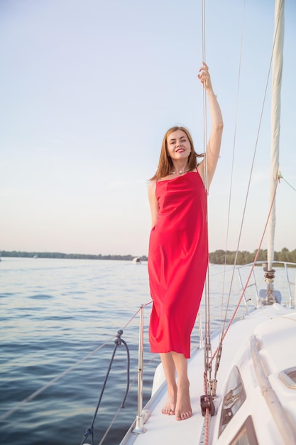 Beautiful woman relaxing on the nose of the yacht at a sunny summer day at the river