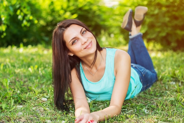 幸せそうに見えて笑顔で草の上で屋外でリラックスした美しい女性