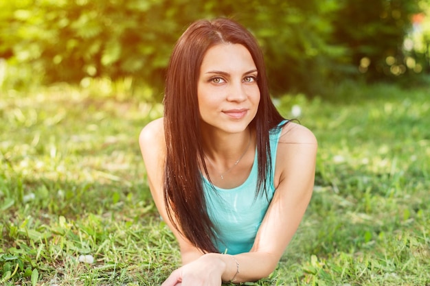 Beautiful woman relaxing outdoors on grass looking happy and smiling