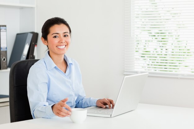 Beautiful woman relaxing with her laptop while enjoying a cup of coffee