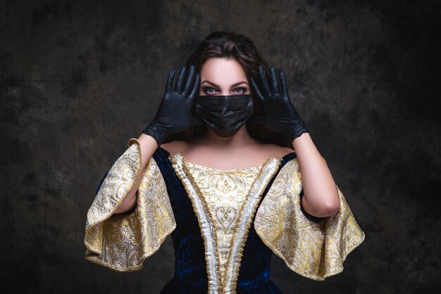 Beautiful woman in renaissance dress, face mask and gloves , coronavirus, covid-19 protection concept.