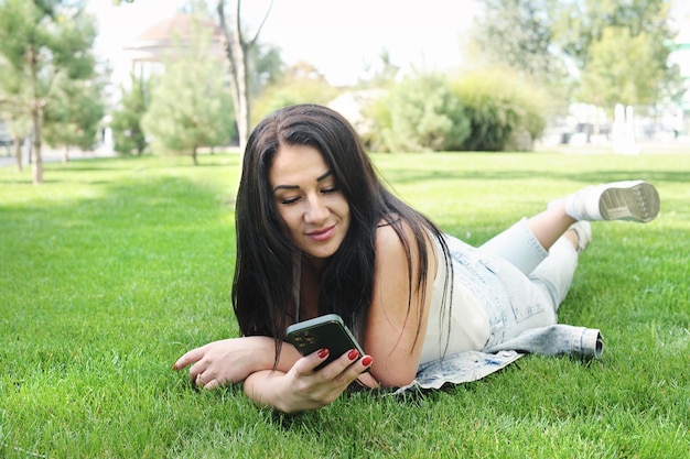 Красивая женщина отдыхает в городском парке и просматривает свои социальные сети