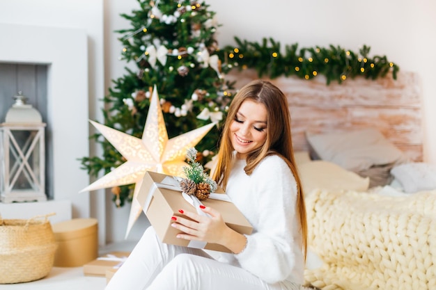 Bella donna che riposa avvolgendo regali per natale e decorando l'albero per la celebrazione