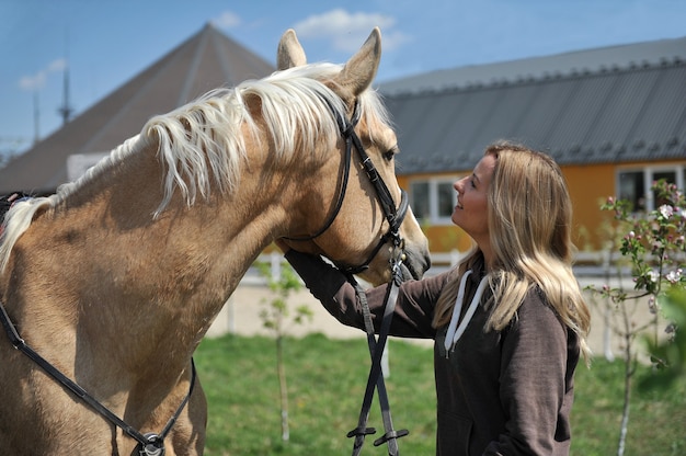 Beautiful woman rider jockey having fun with her favorite horse. Tenderness, love and animals concept.