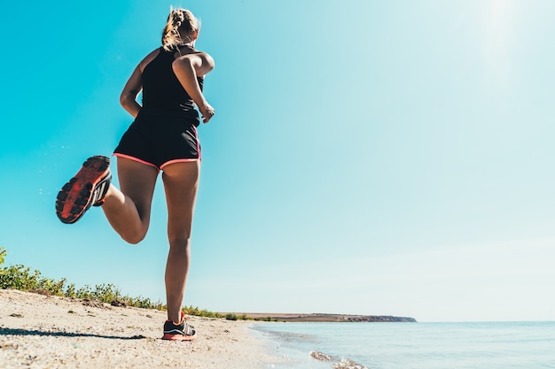 The beautiful woman running along the sea coast