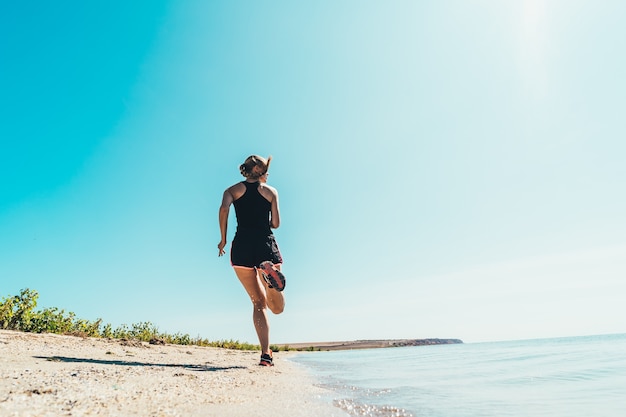 The beautiful woman running along the sea coast