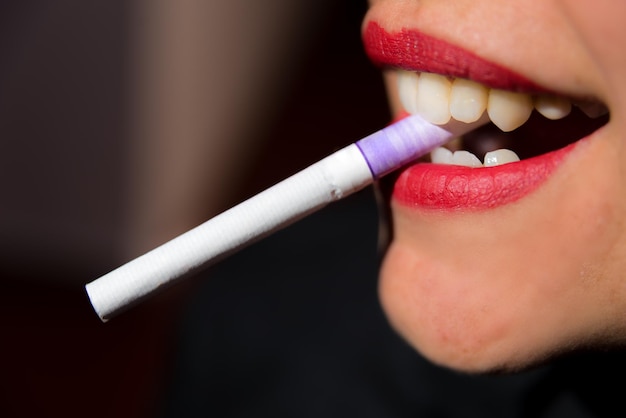 Beautiful woman's mouth biting a cigarette black background