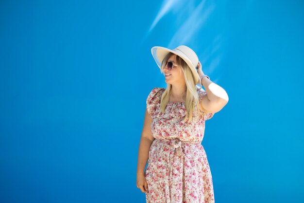 Foto bella donna su uno sfondo blu saturo delle mura della città con raggi di sole in estate una bella donna sorride e guarda verso lo spazio vuoto per inserire un'iscrizione copia spazio