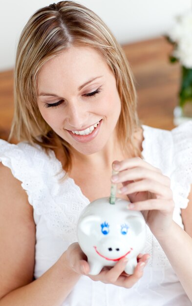 Beautiful woman saving money in a piggy-bank