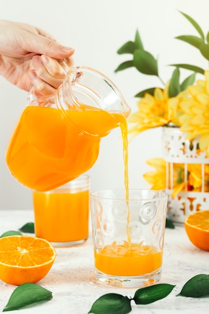 A beautiful woman serves freshly made orange juice in a glass