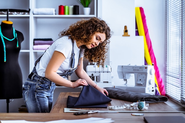 The beautiful woman sews on the table