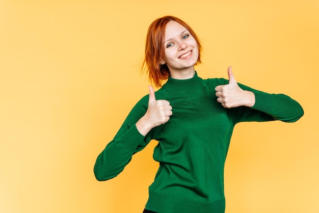 Beautiful woman showing thumbs up isolated on yellow background