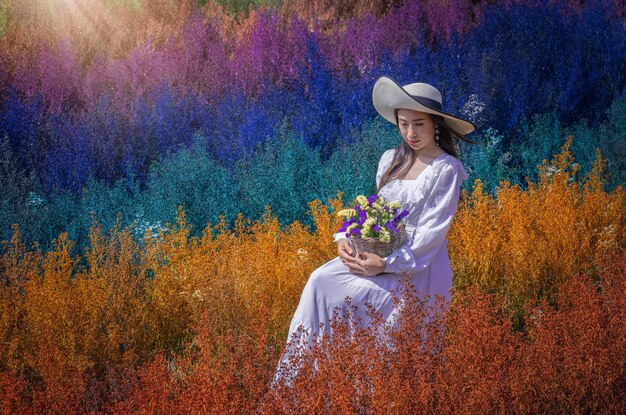 Foto una bella donna si siede tra i tagliatori di fiori nei colori dell'arcobaleno nella provincia di chiang mai in thailandia