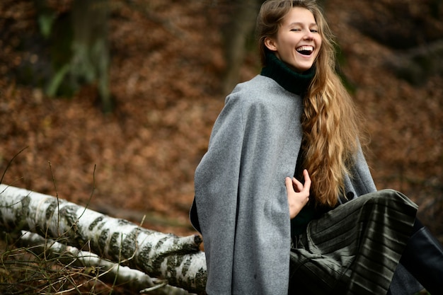 Beautiful woman sits in the woods and laughs