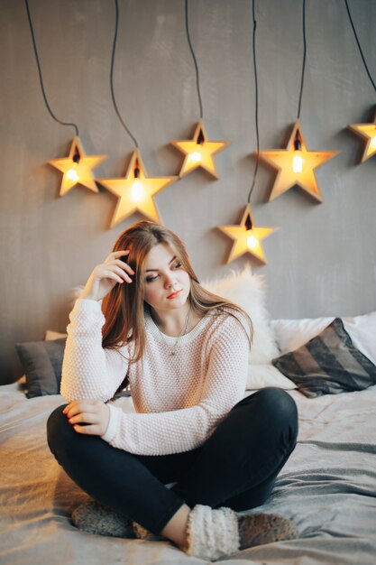 Beautiful woman sitting on bed at home