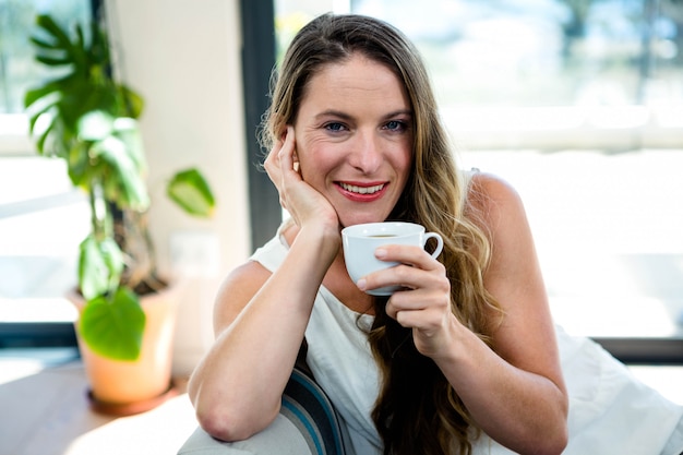 beautiful woman, sitting on the couch, smiling and drinking coffee