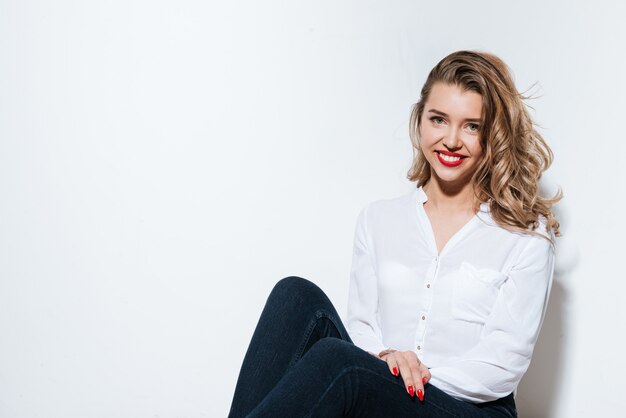 Beautiful woman sitting on the floor on white wall