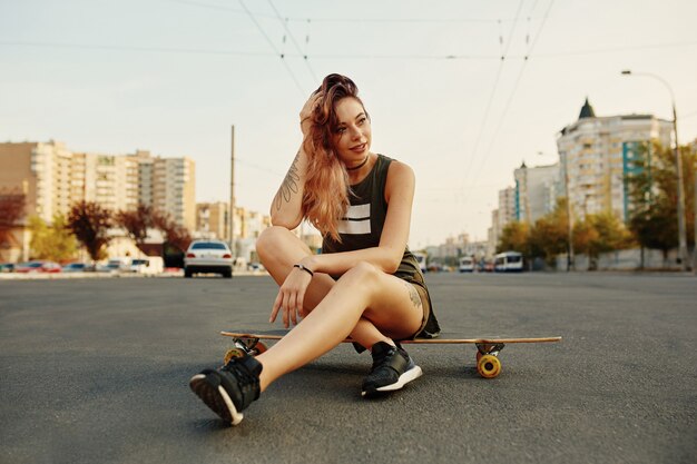 Красивая женщина, сидящая на Longboard на городской площади