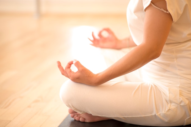 beautiful woman sitting in lotos pose and practicing meditation in yoga hall