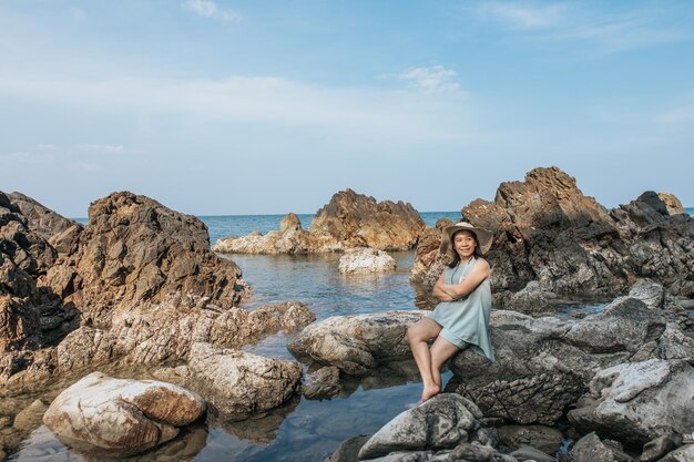 Beautiful woman sitting on rock over sea