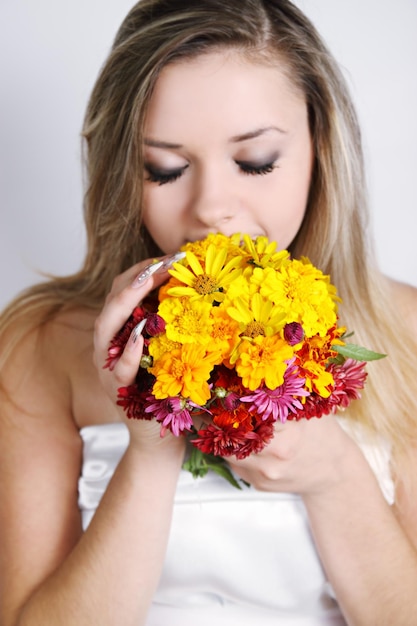 Beautiful woman smelling a bouquet of autumn flowers