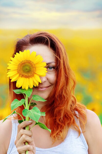 Beautiful woman smiles and covers her face with a sunflower