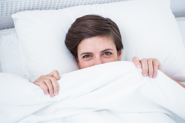 Beautiful woman smiling under the duvet