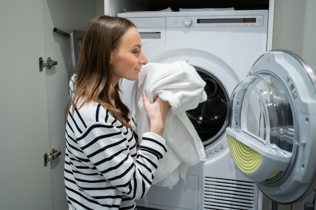 Beautiful woman sniffs white towels after washing in the washing machine