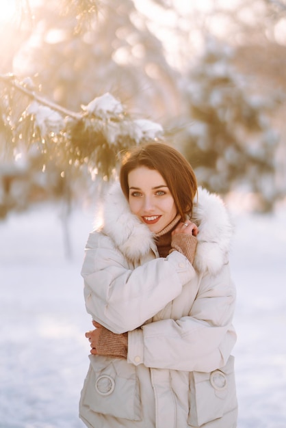 눈 덮인 공원에서 아름 다운 여자입니다. 화창한 겨울 날에 걷는 젊은 아가씨.