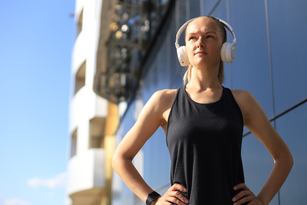 Beautiful woman in sports clothing looking at camera while exercising outdoors.