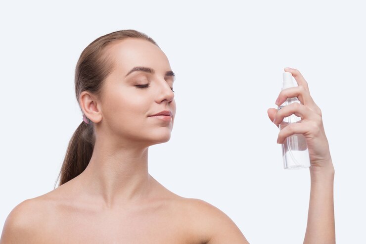 Beautiful woman spraying on face isolated on white background