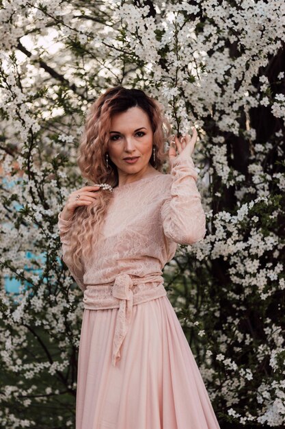 Foto una bella donna in un giardino primaverile vicino ai fiori di ciliegio giardino in fiore