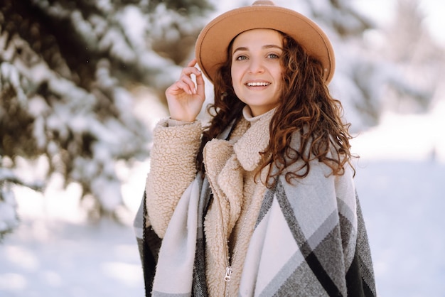 Beautiful woman standing among snowy trees and enjoying first\
snow happy time christmas