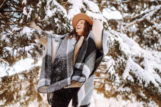 Beautiful woman standing among snowy trees and enjoying first\
snow happy time christmas