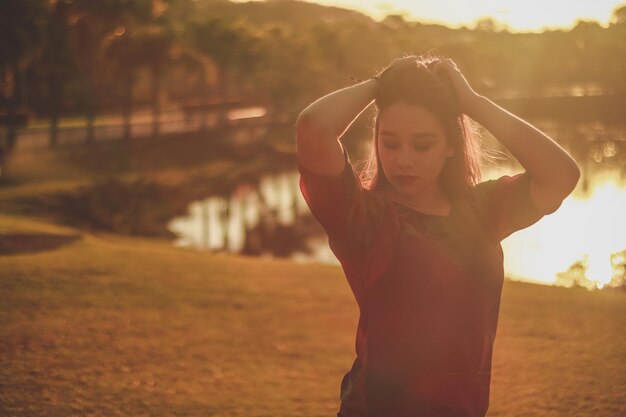 写真 夕暮れの場で湖のそばに立っている美しい女性