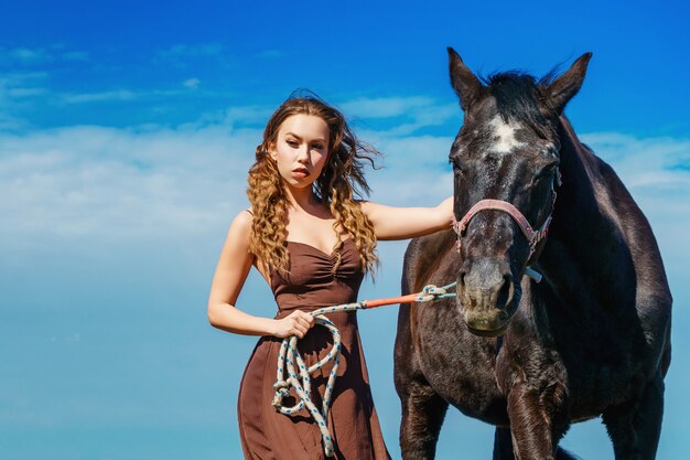 Beautiful woman standing in a field with a horse