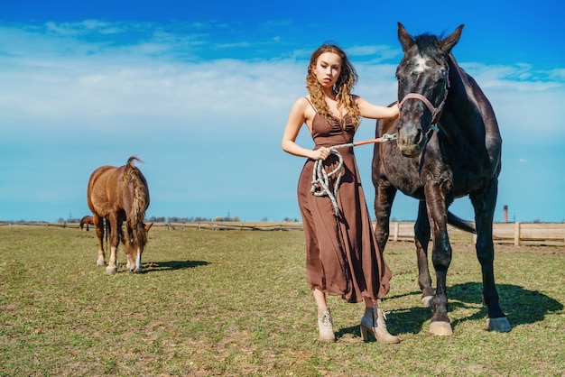 Beautiful woman standing in a field with a horse