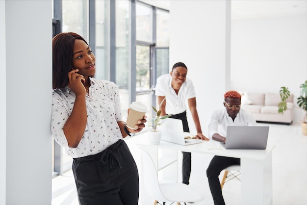 Beautiful woman standing in front of colleagues Group of african american business people working in office together