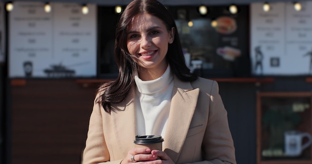 Beautiful woman standing outdoor holding coffee Closeup relaxing woman with coffee to go