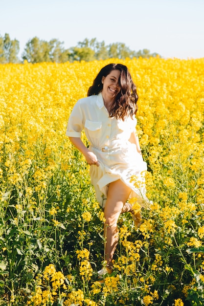 Beautiful woman standing in rapeseed field summertime