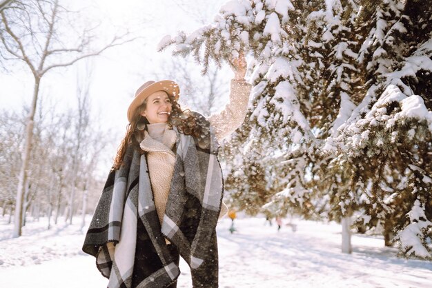 Красивая женщина, стоящая среди заснеженных деревьев и наслаждающаяся первым снегом Счастливое время Рождества