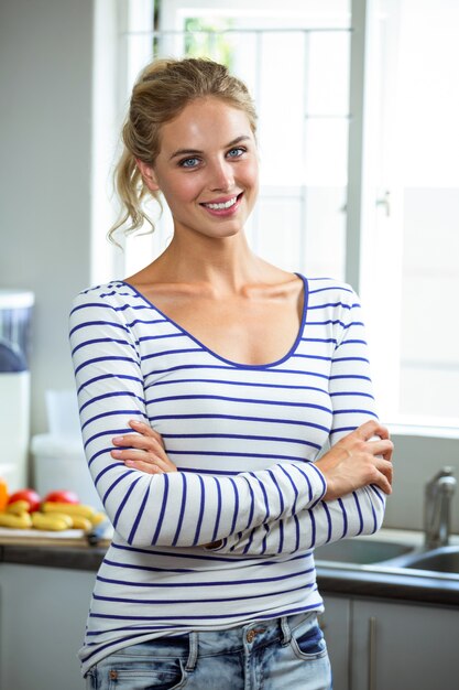 Beautiful woman standing with arms crossed in kitchen