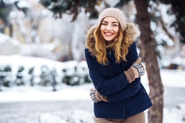 Beautiful woman stands among snowy trees in winter forest\
fashion woman in the winter park