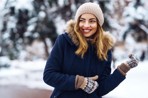 Beautiful woman stands among snowy trees in winter forest Fashion woman in the winter park