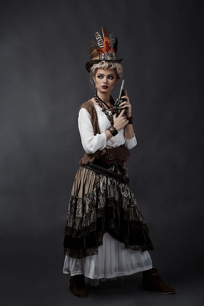 Beautiful woman in steampunk style costume with hat and handgun