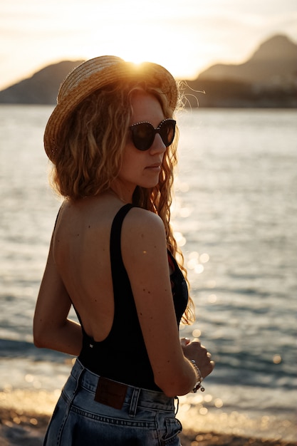 Bella donna in un cappello di paglia vicino al mare