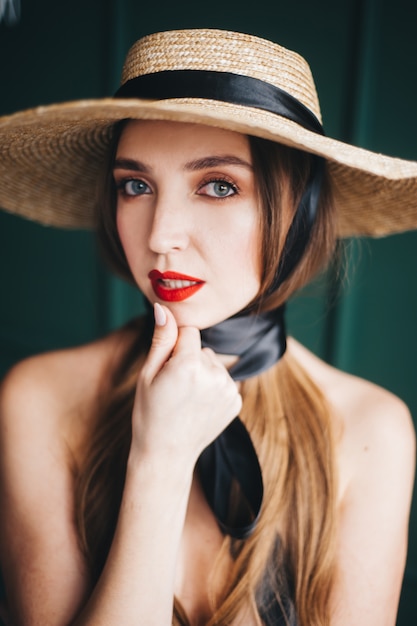 Beautiful woman in a straw hat with black ribbons.